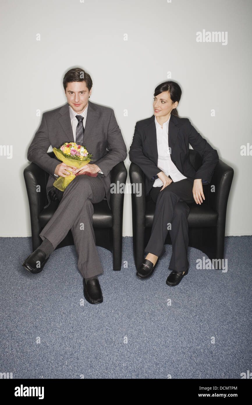 Male office worker with flowers sitting next to female colleague Stock Photo Alamy
