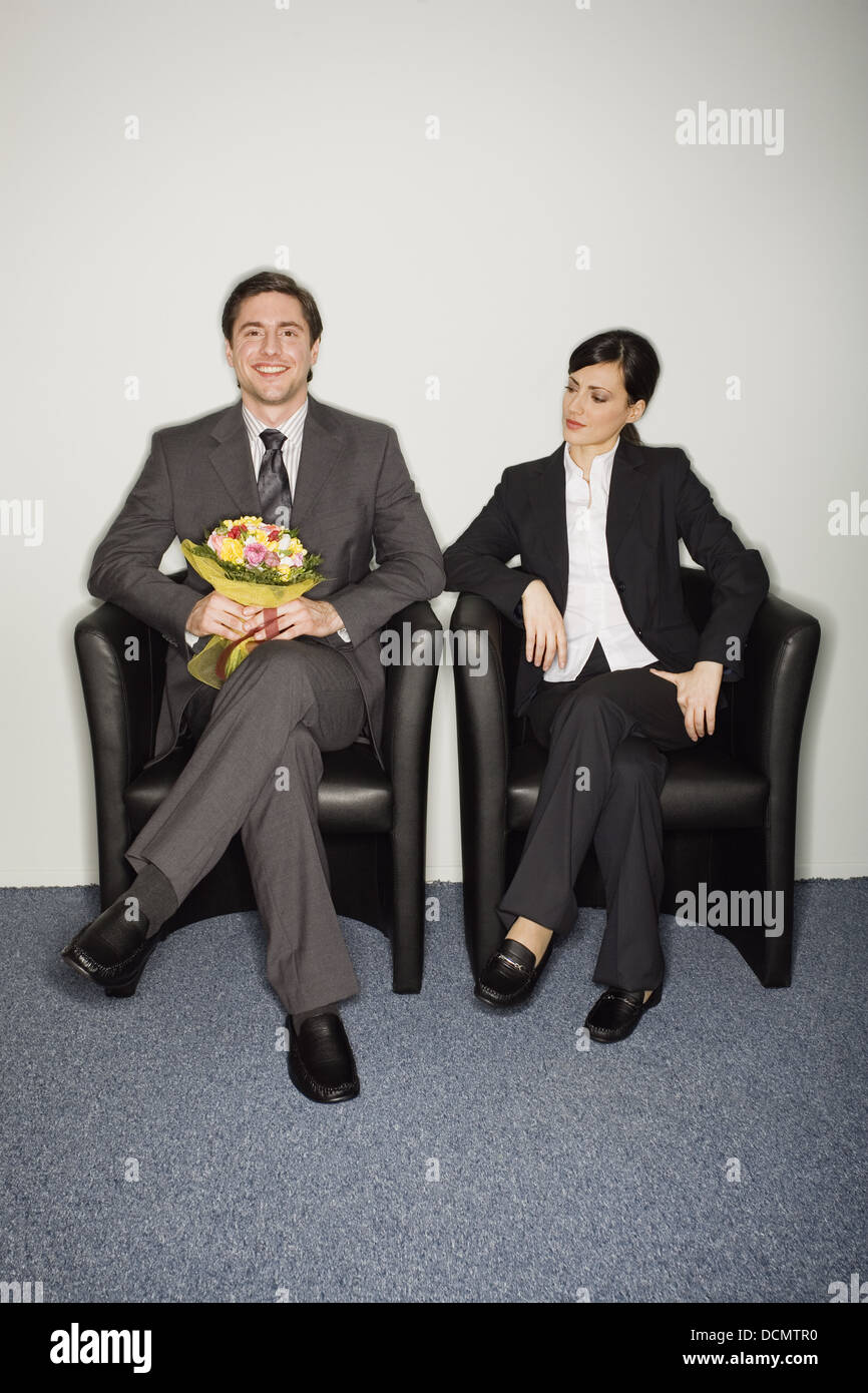 Male office worker with flowers sitting next to female colleague Stock Photo Alamy