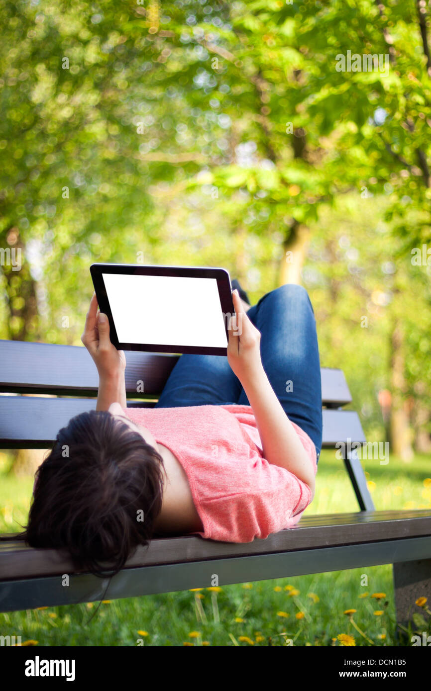 Young woman using tablet outdoor laying on grass Stock Photo