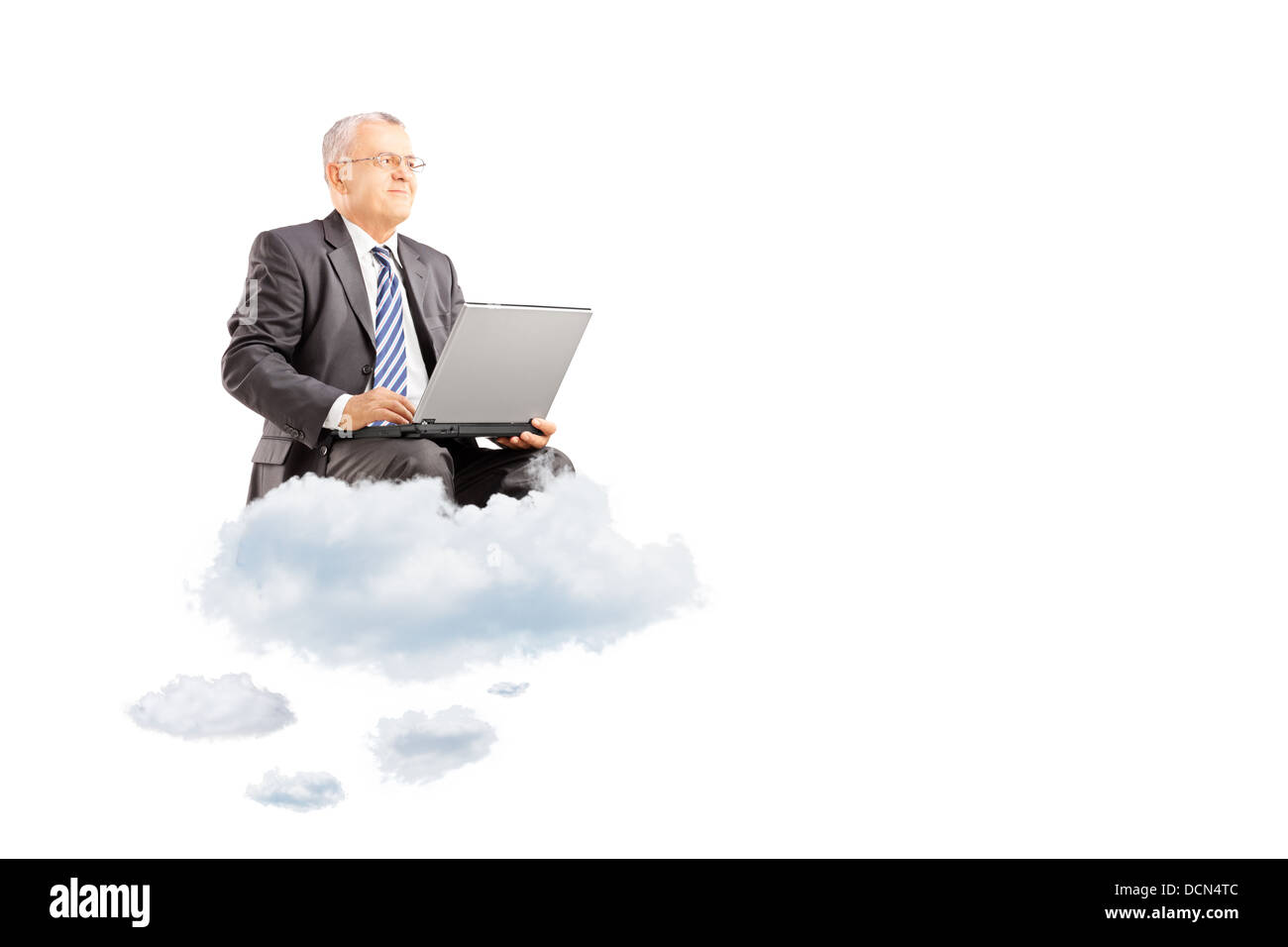 Mature businessman wearing suit and flying on clouds with laptop Stock Photo