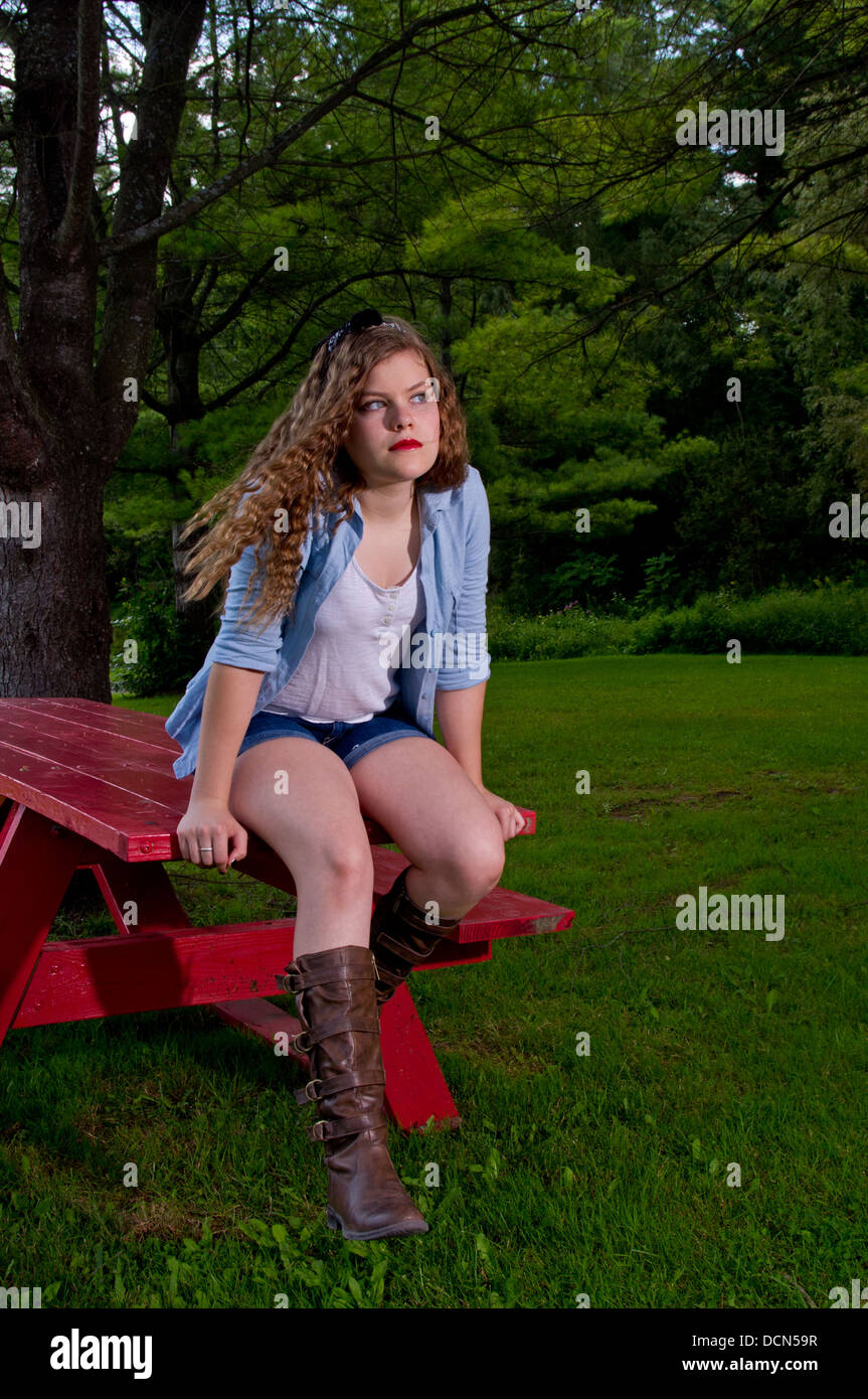 Teen Girl in a park sitting on a picnic table Stock Photo - Alamy
