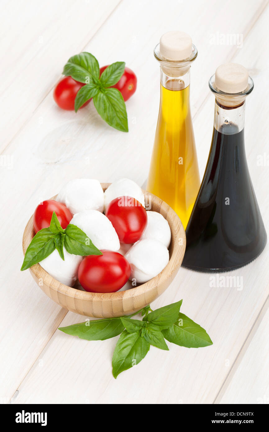 Mozzarella cheese with cherry tomatoes, basil and olive oil with vinegar on white wood table Stock Photo