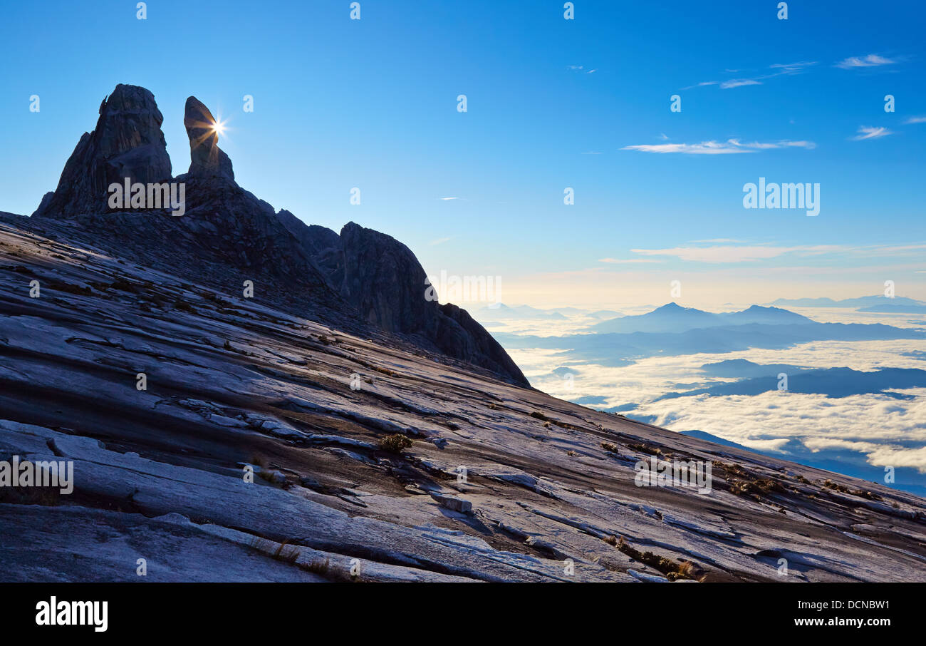 Starburst sunrise behind Donkey's Ears peak on Mount Kinabalu in Sabah Borneo with a view of cloud wreathed mountains Stock Photo