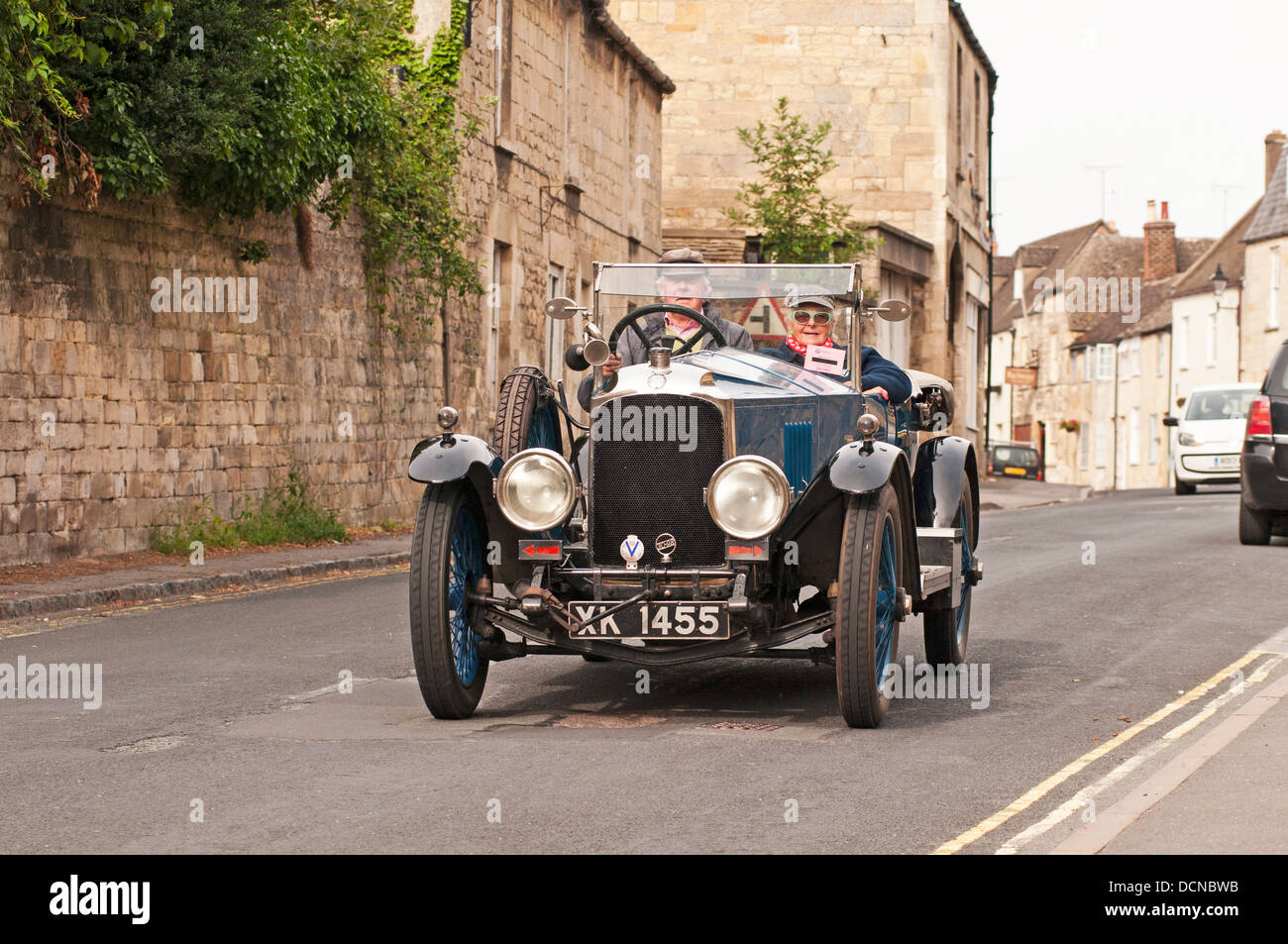 Vintage car driving through village Gloucestershire England