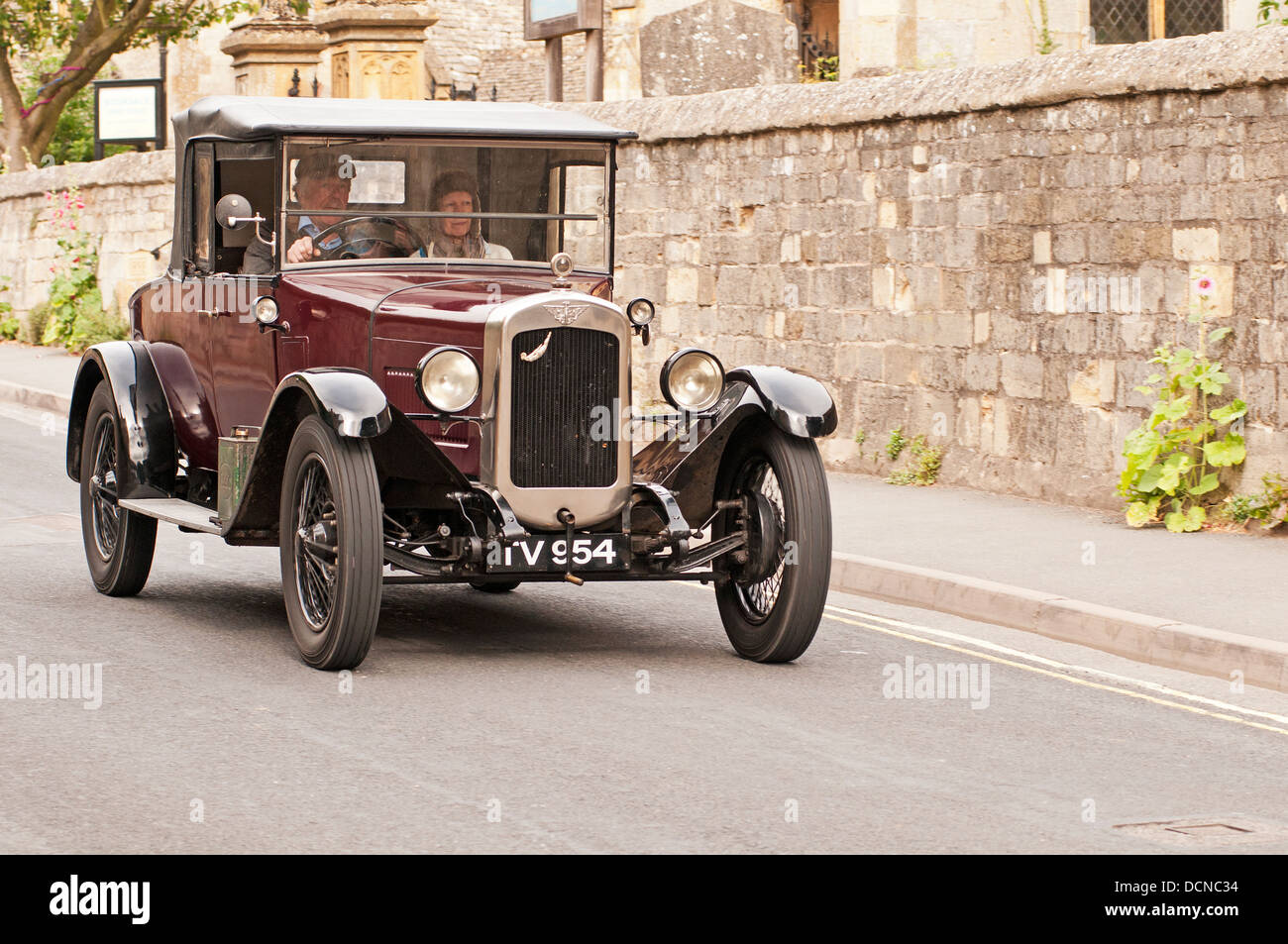 A vintage car driving through Village Gloucestershire