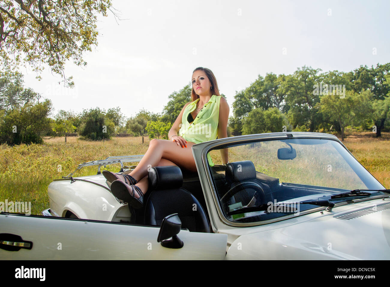 Attractive young woman posing leaning on convertible car at sunset - Stock  Image - Everypixel