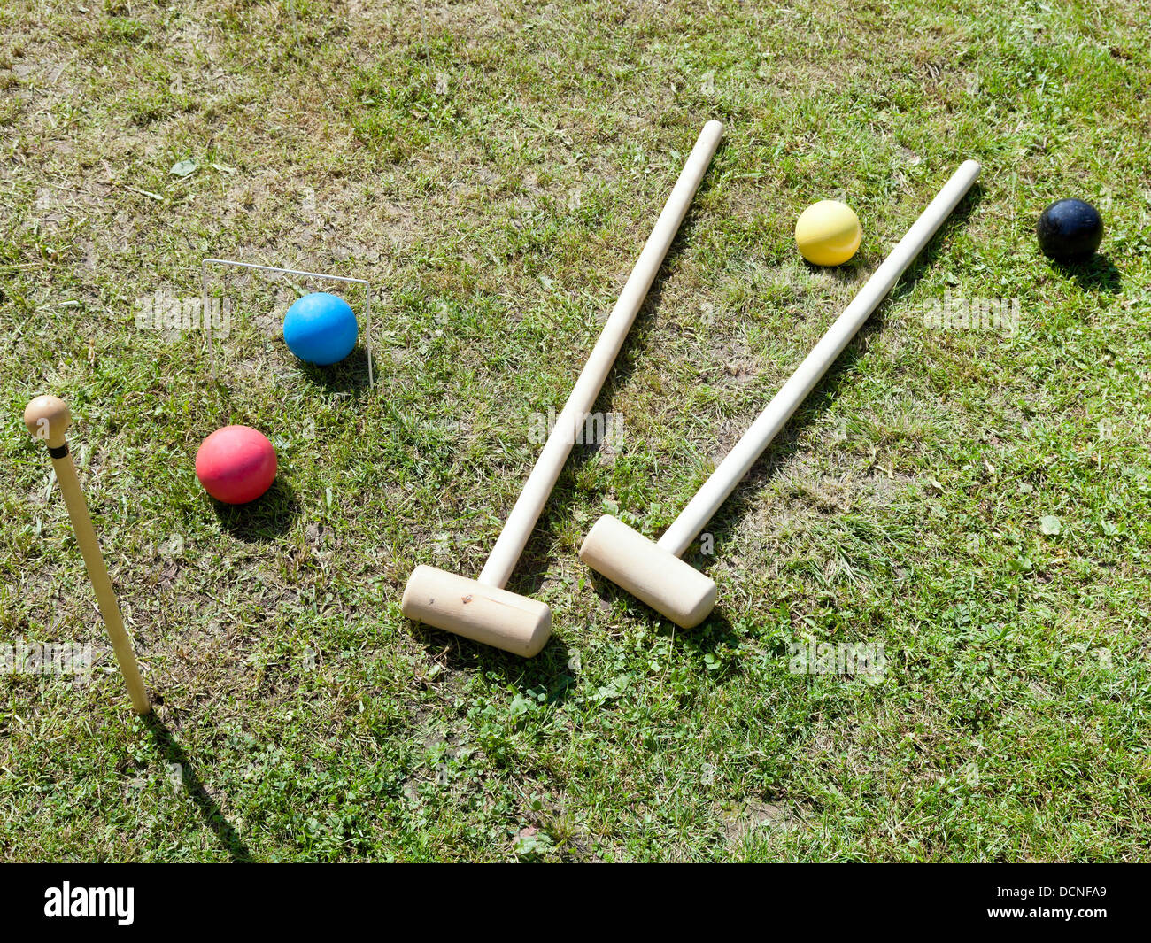 wooden croquet equipment for game of croquet on green lawn in summer