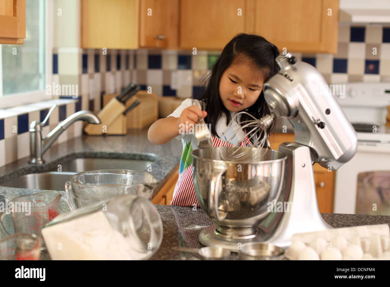 Young girl helping mother bake in kitchen Stock Photo