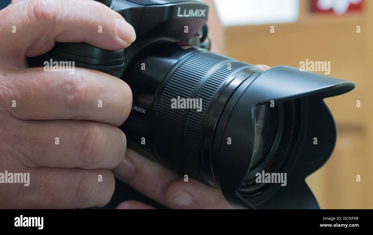 A handheld Panasonic Lumix GH3 camera with 14-140mm f3.5-f5.6 zoom lens Stock Photo