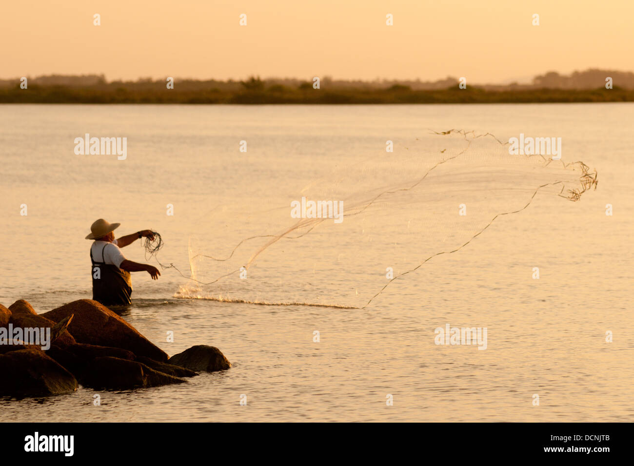 Immigrant family using castnet to catch food fish mullet in