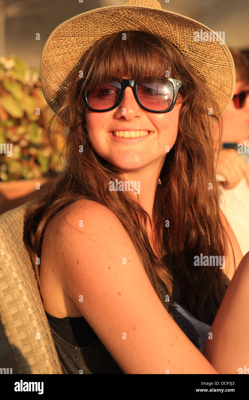 Pretty teenage girl with sun hat and sunglasses as the sun is setting Stock Photo