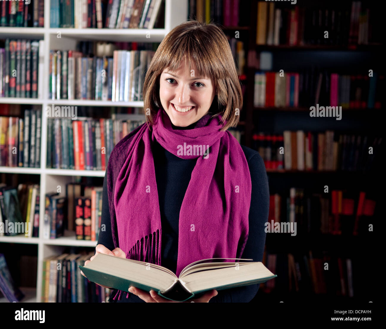 Smiling student in library holding open book Stock Photo - Alamy