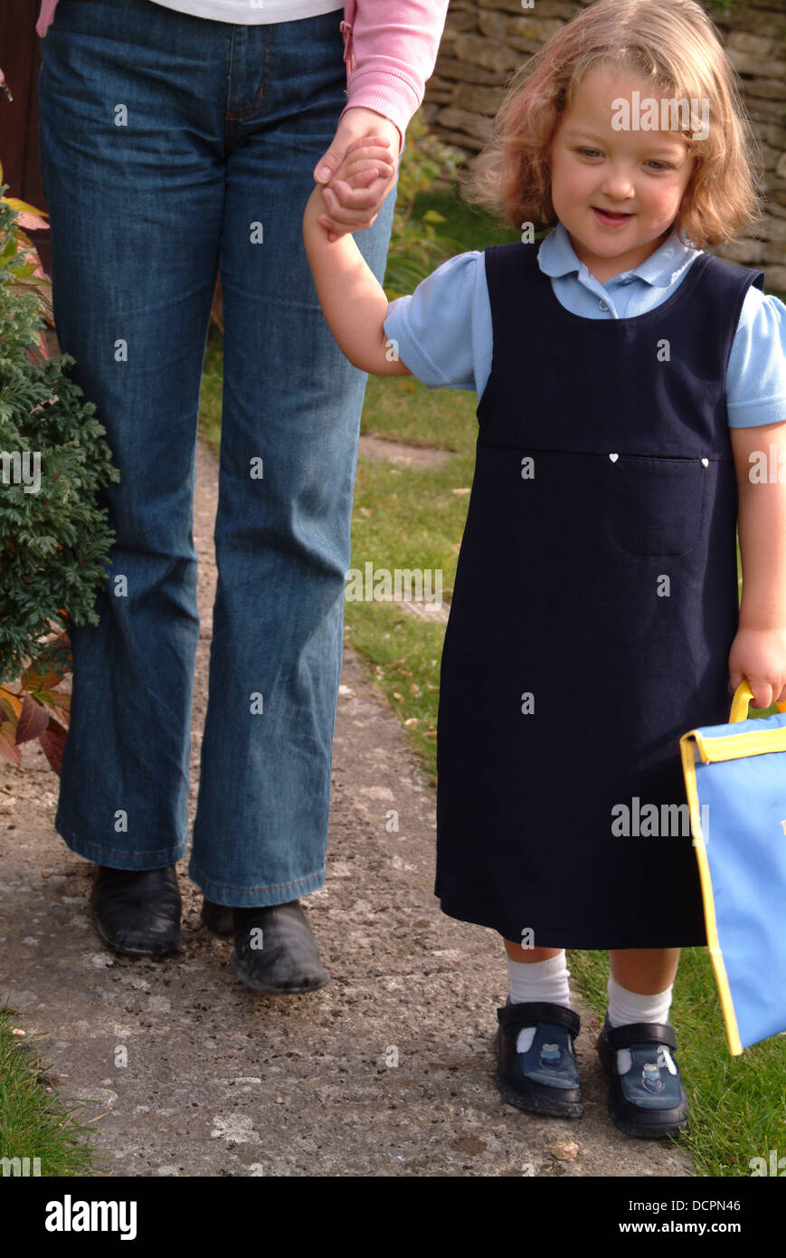 Mother and young girl wearing school uniform on their way to school