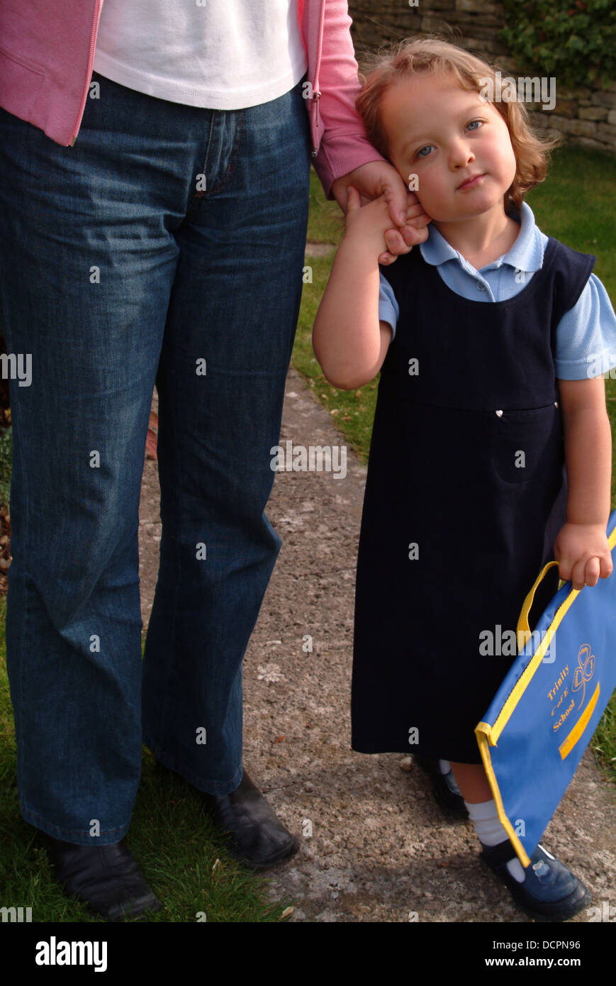 Mother and young girl wearing school uniform on their way to school ...