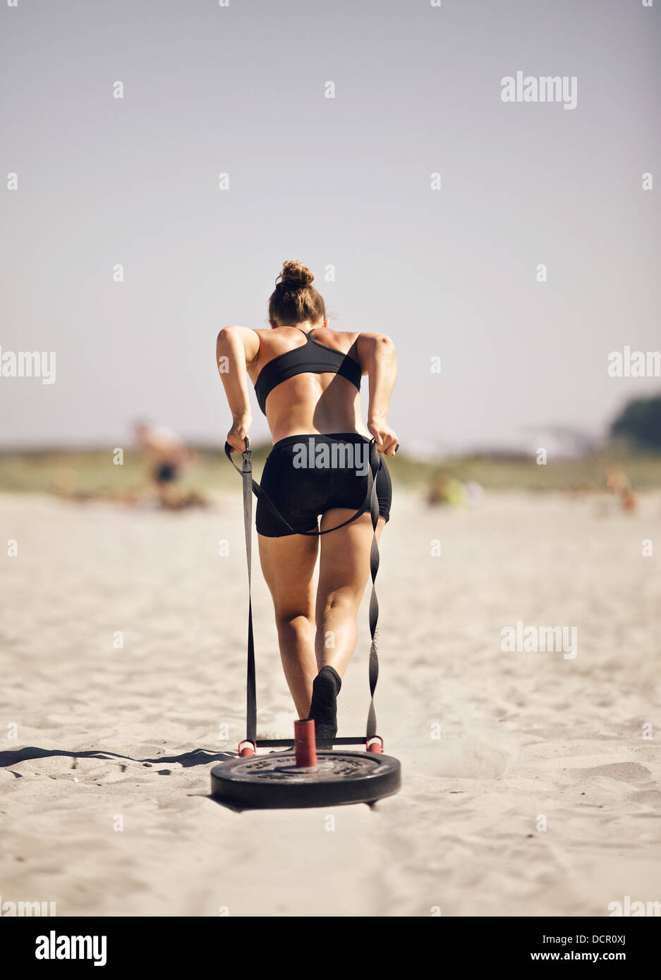 Woman pulling sled during a crossfit beach workout Stock Photo Alamy