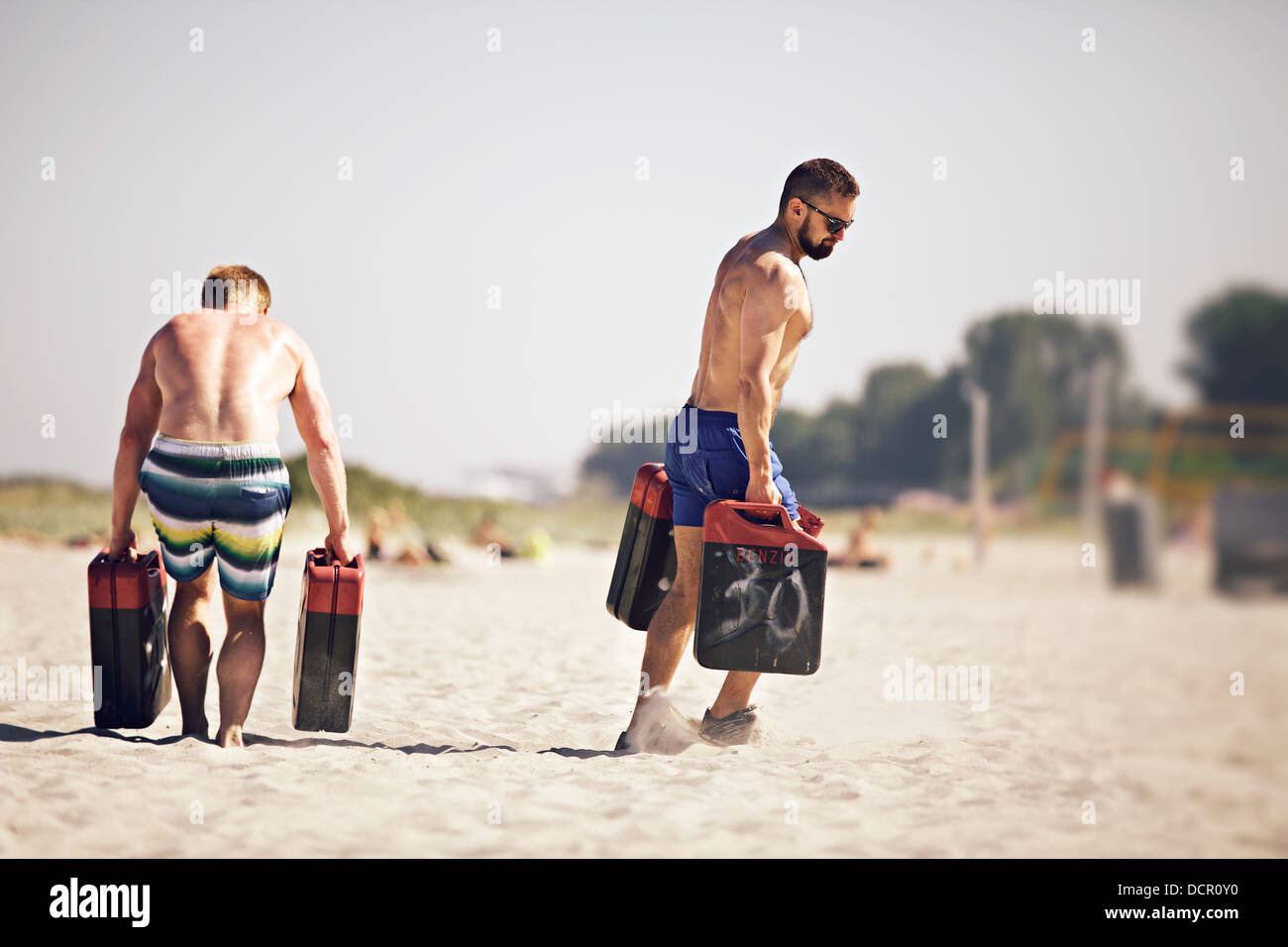 Two male crossfitters running with jerrycans at a crossfit beach