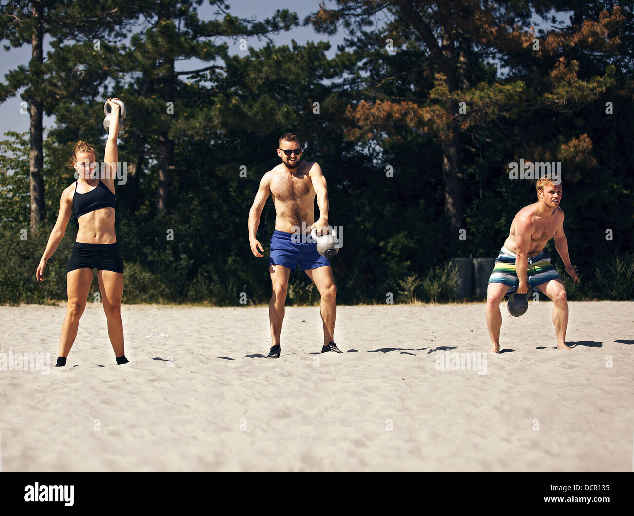 Three people doing crossfit workout on a beach Stock Photo