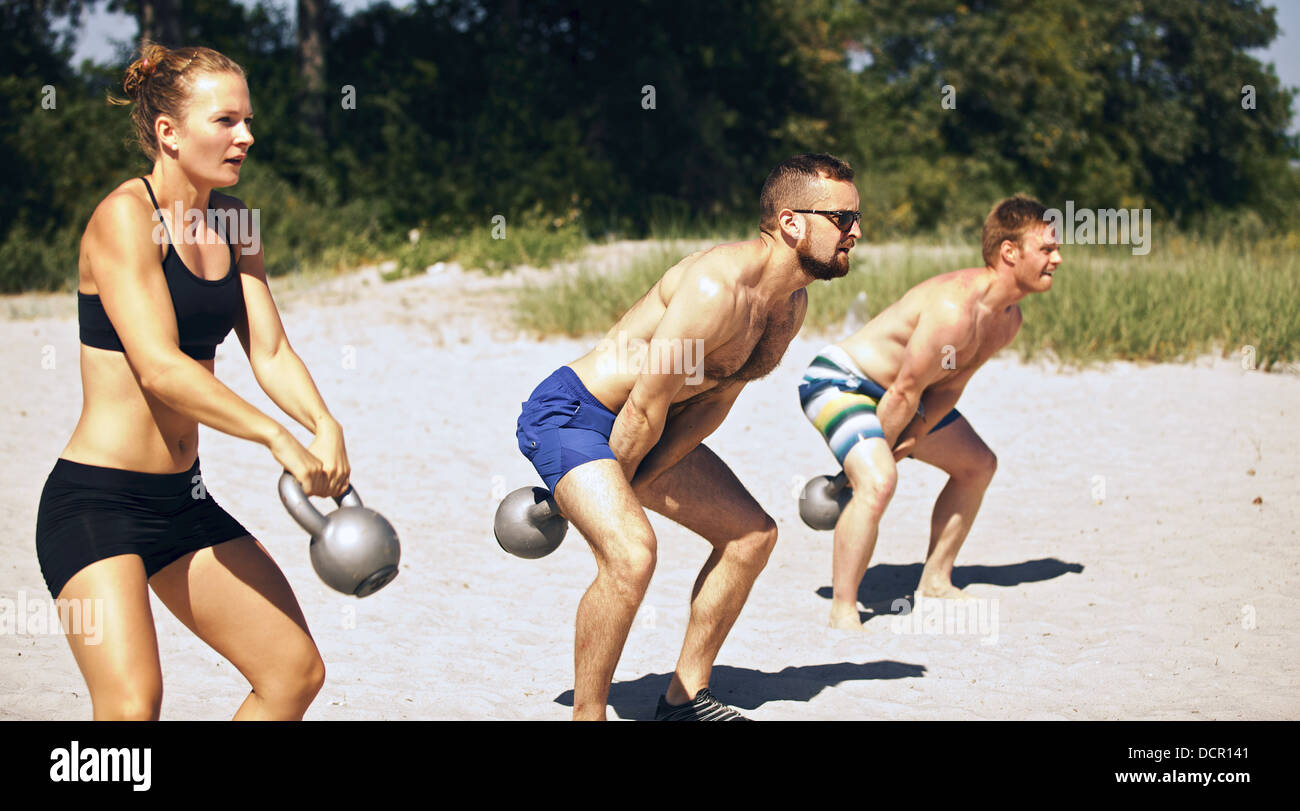 Group doing crossfit workout on beach on a hot summer day Stock Photo