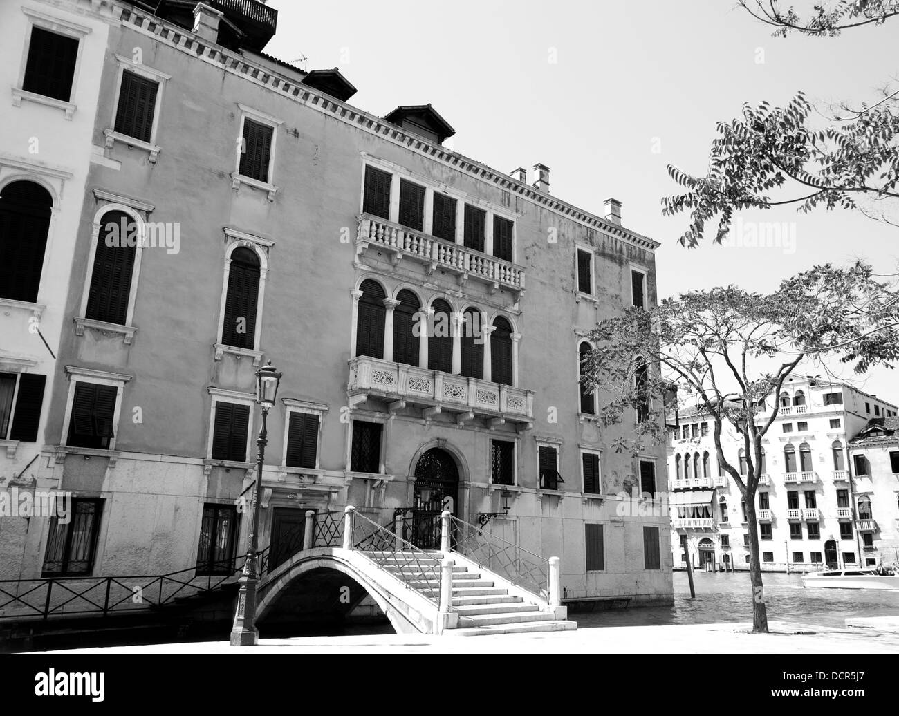 A black and white photograph of a Venietian building and small bridge, next to the Canal Grande, Venice, Italy Stock Photo