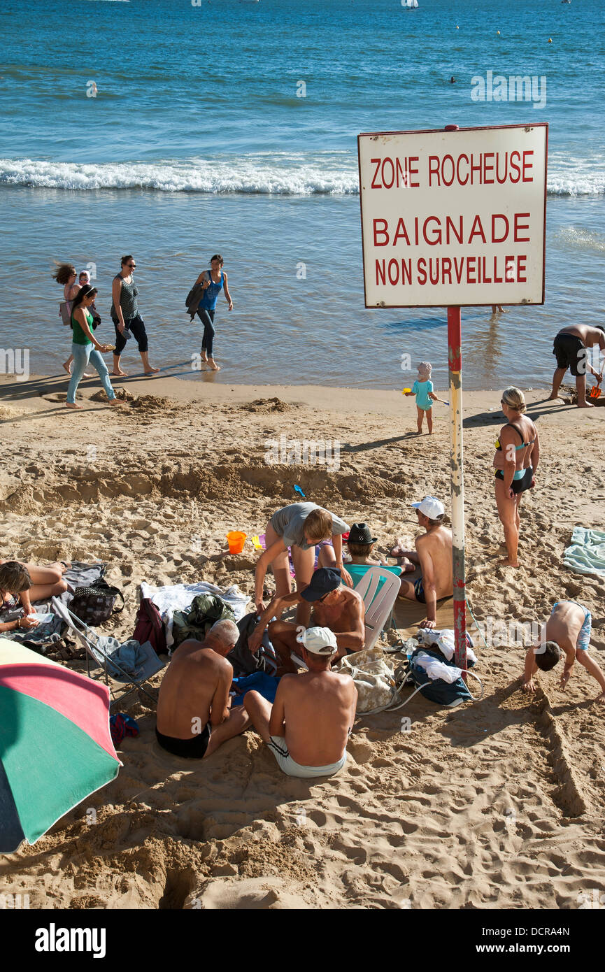 seaside beach sand warning notice sign rocks rocky coastline coast coastal zone lifeguard Beach and warning notice at Les Sables Stock Photo