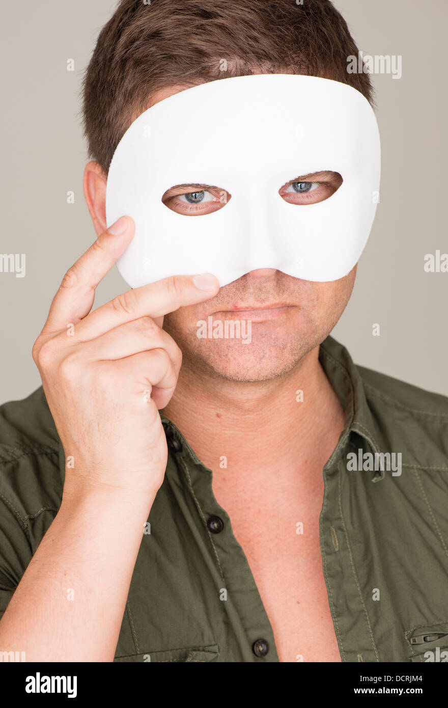 Pensive and serious man hiding behind white mask Stock Photo