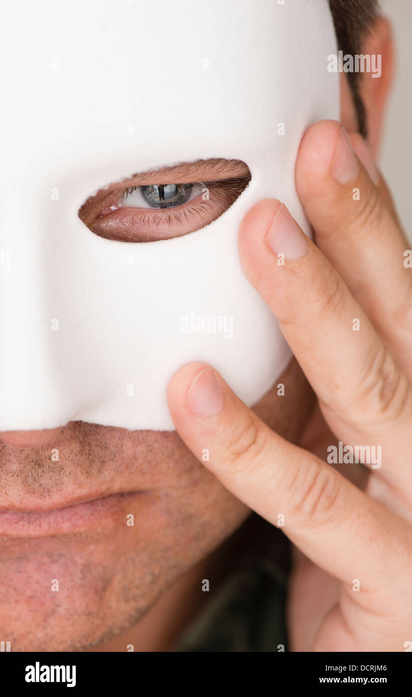 Pensive and serious man hiding behind white mask Stock Photo