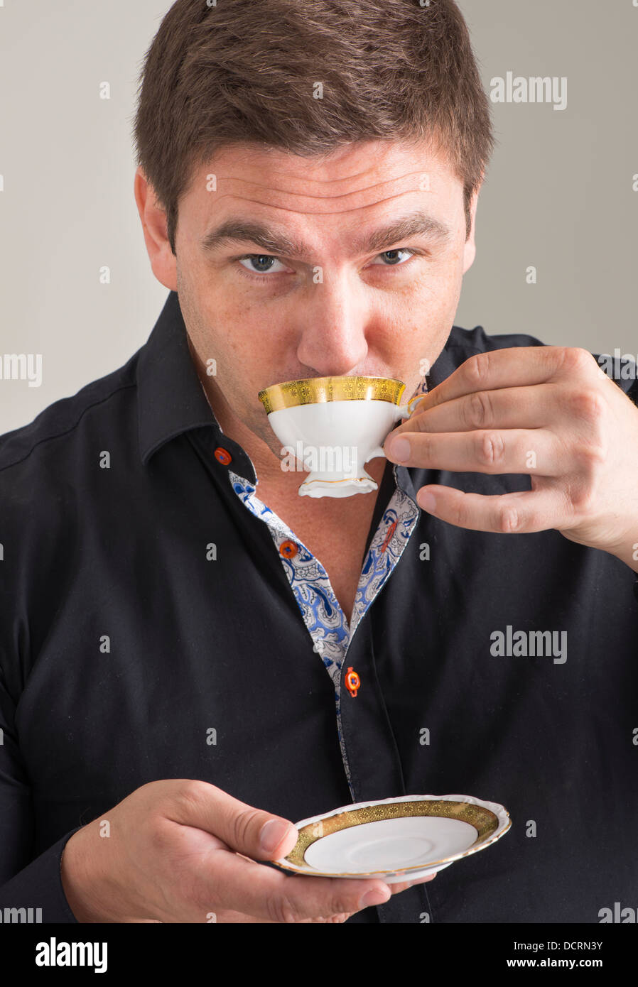 Businessman in black unbuttoned shirt relaxing with a cup of coffee Stock Photo