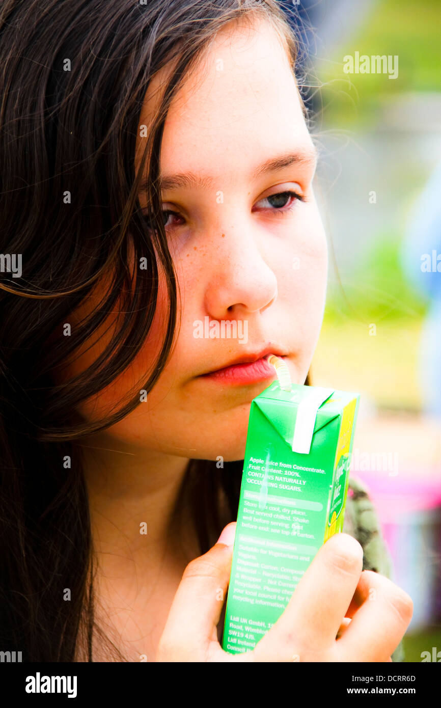 Pre teen girl drinking juice from carton looking glum Stock Photo