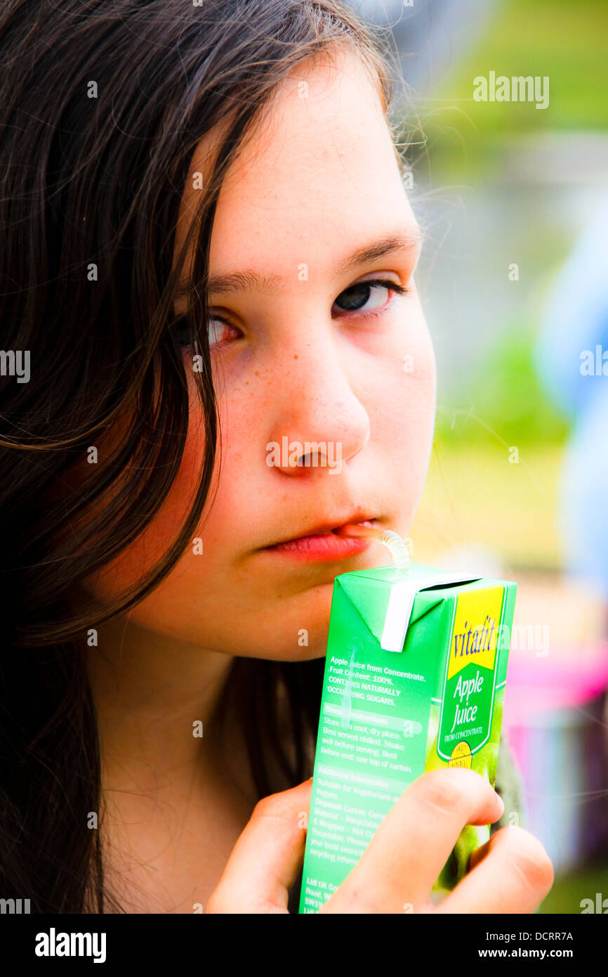 Pre teen girl drinking juice from carton looking glum Stock Photo