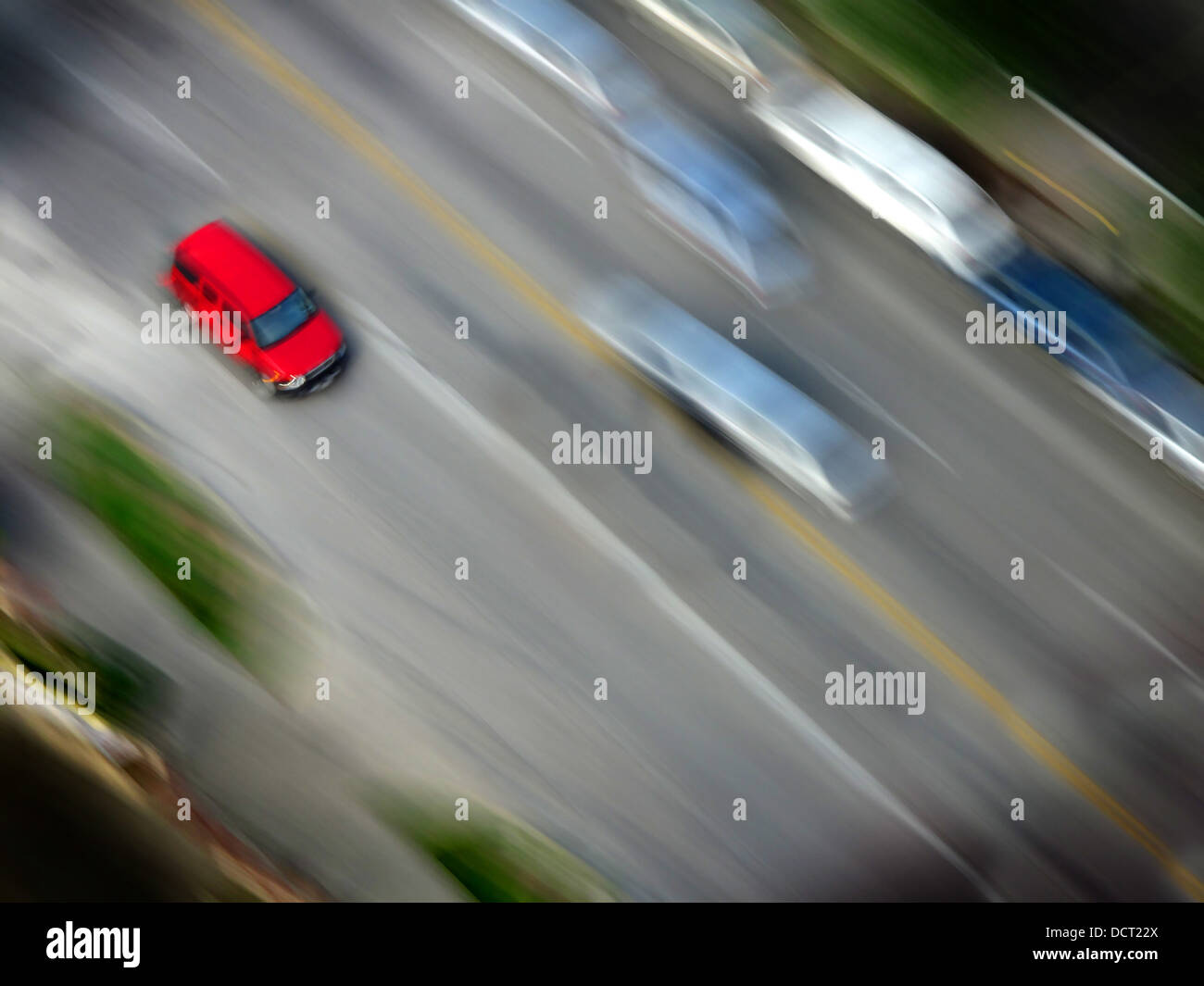 Speedy red car driving along road with blurred background Stock Photo