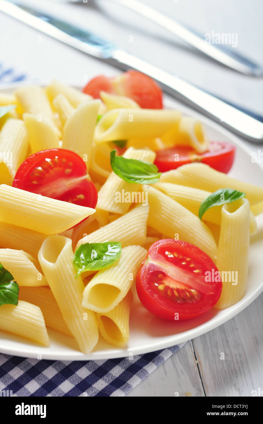 Penne pasta with cherry tomatoes and basil closeup Stock Photo - Alamy