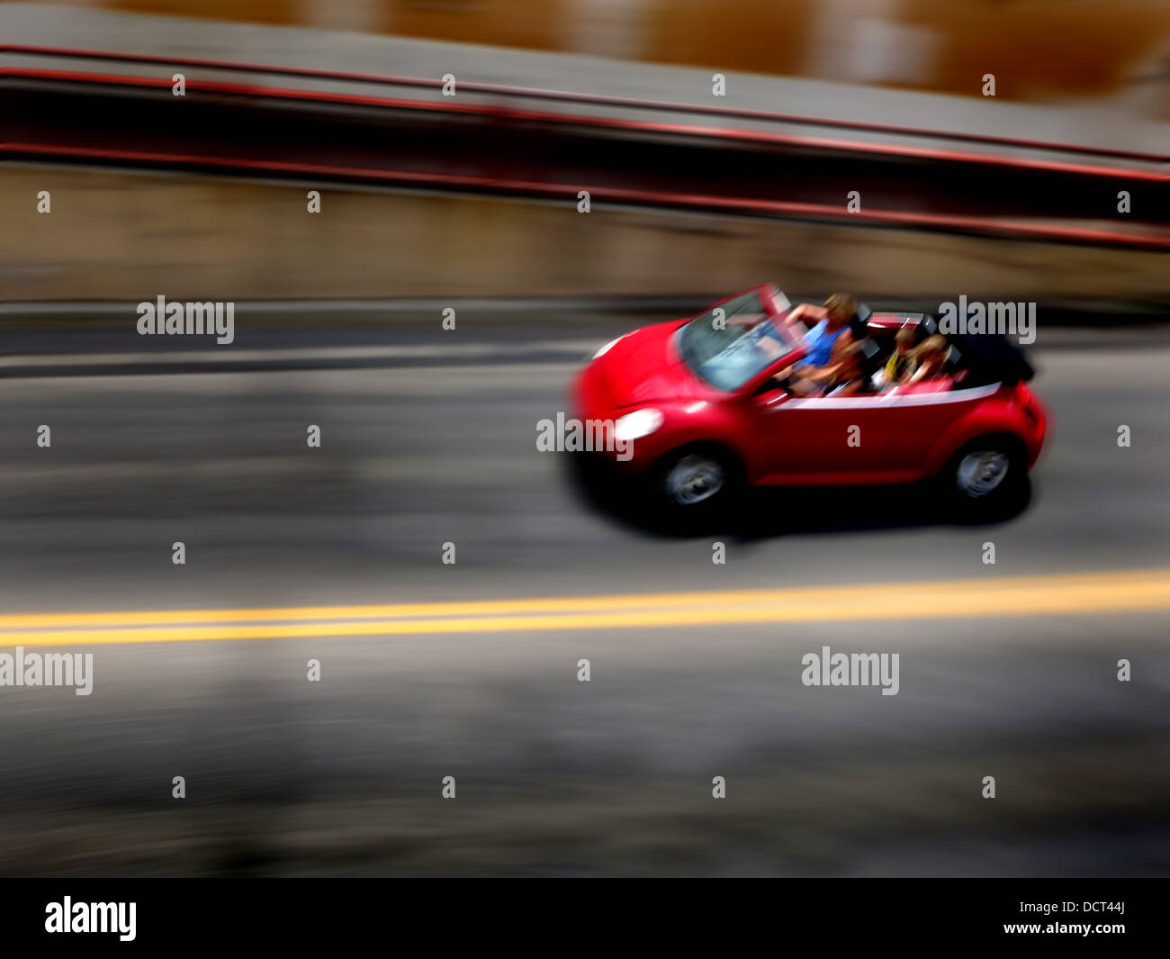 Red Car driving along road with blurred background Stock Photo