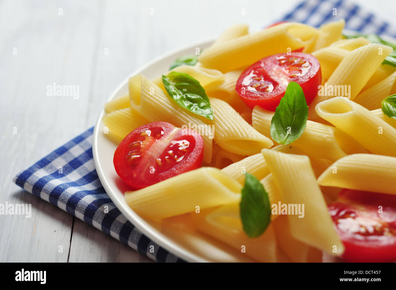 Penne pasta with cherry tomatoes and basil closeup Stock Photo