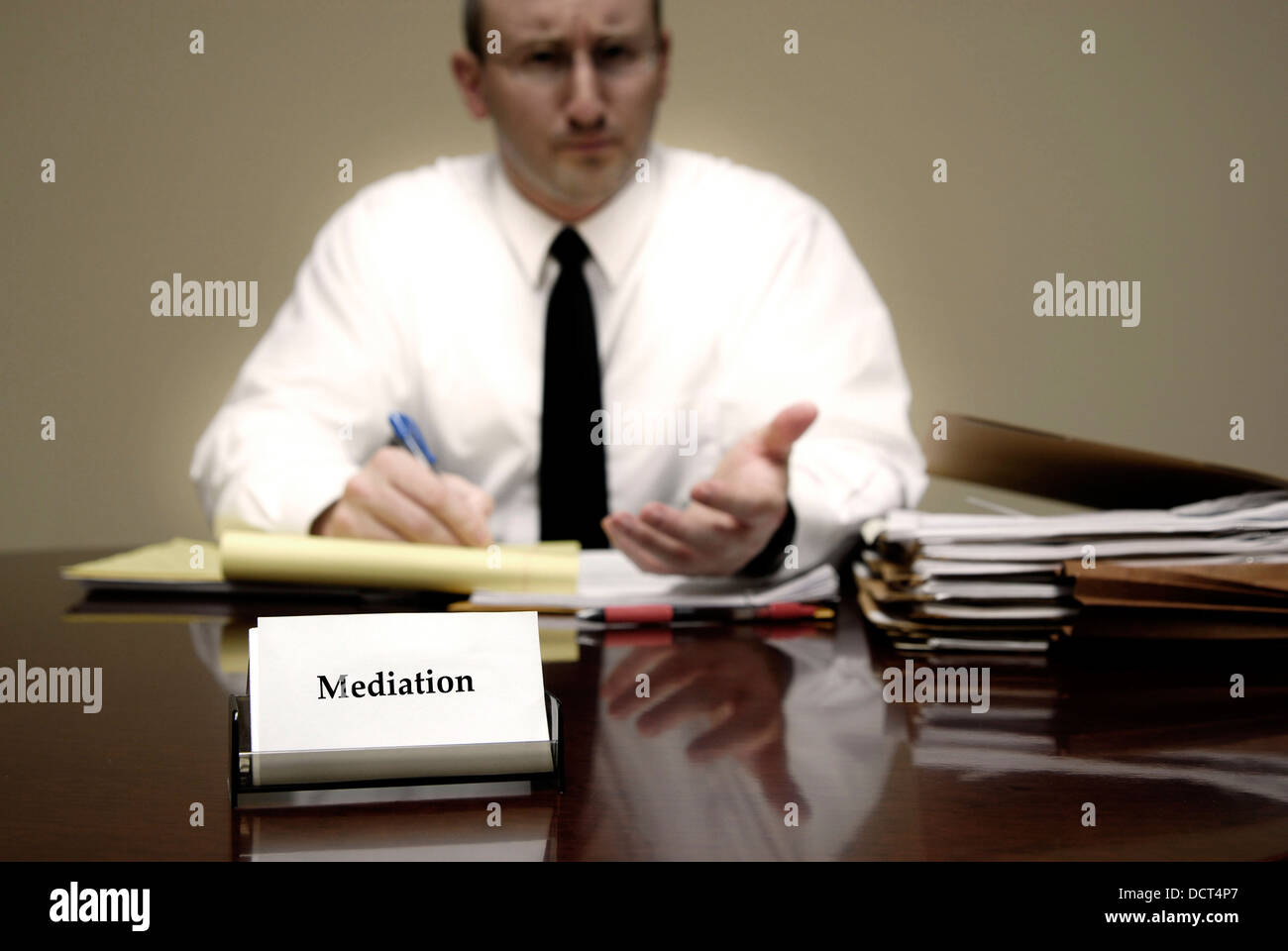 Attorney at Law sitting at desk holding pen with files with a card for