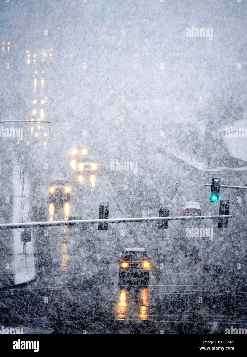 Snowy winter road with cars driving on roadway in snow storm Stock Photo