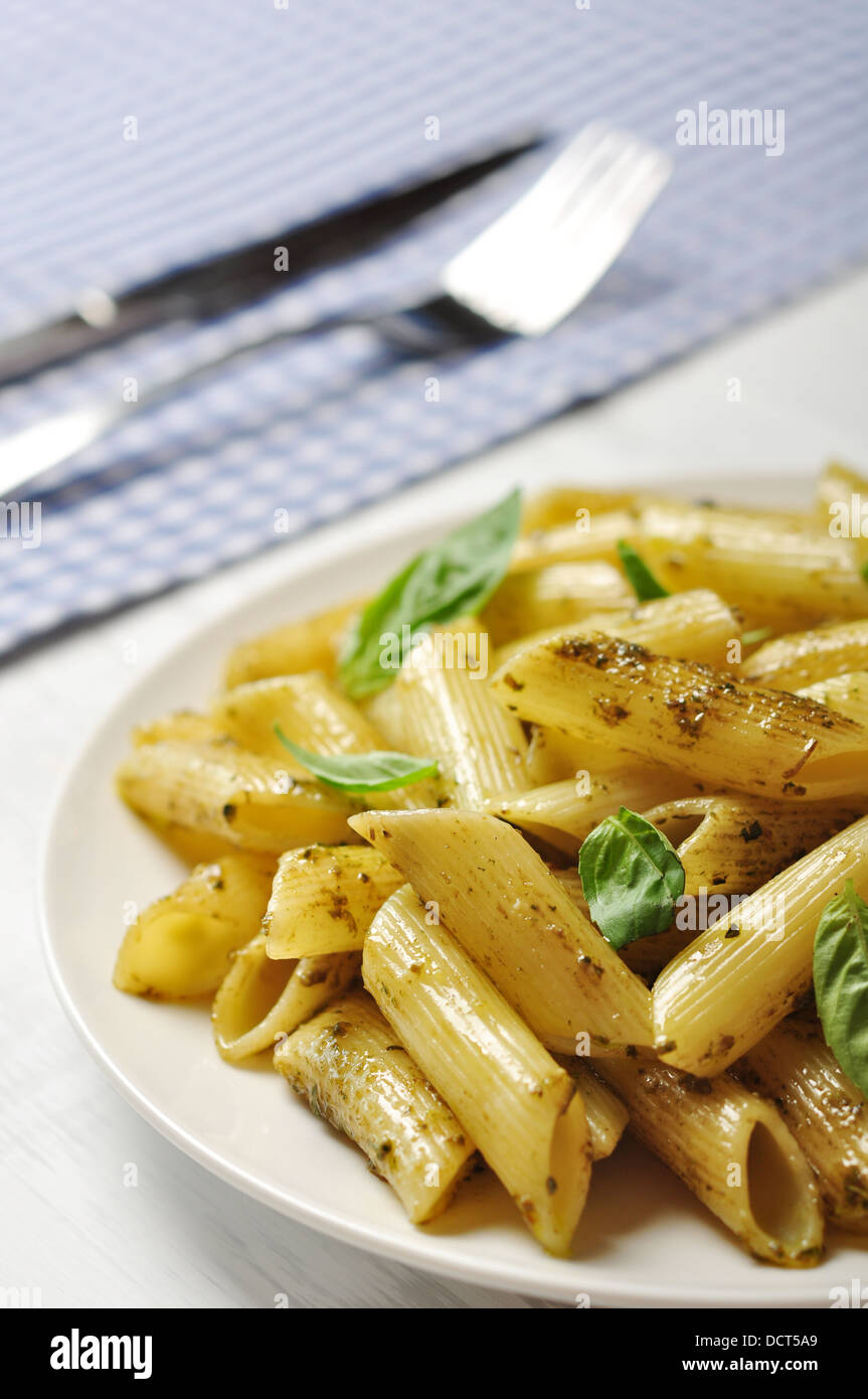 Penne pasta with pesto sauce and basil on white plate Stock Photo