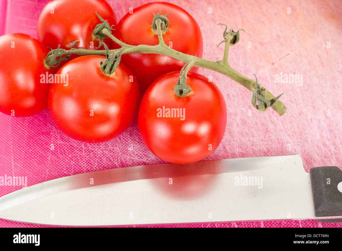 Beautiful tomatoes with kitchen knife on chopping board Stock Photo - Alamy