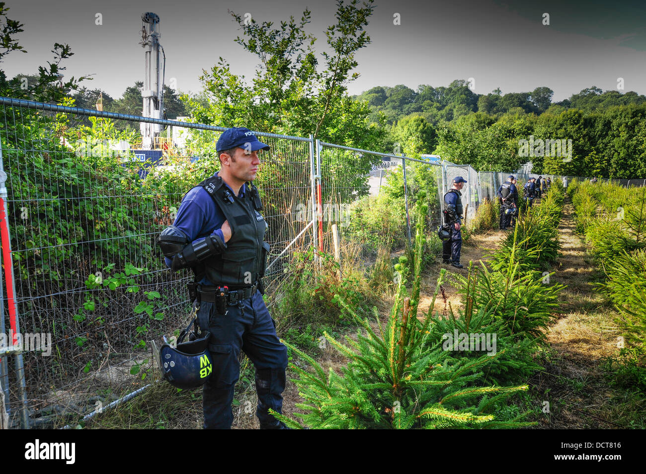 Balcombe, Sussex, UK. 21st Aug, 2013. Police officers guarding Cuadrilla perimeter fence as drilling rig resumes operation in background . Credit:  David Burr/Alamy Live News Stock Photo