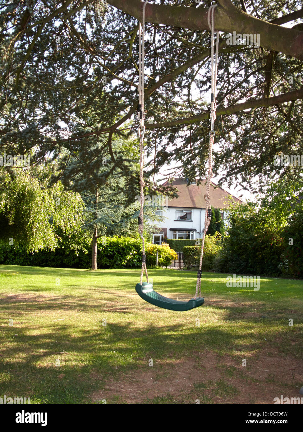 empty childs swing in a garden in the uk Stock Photo