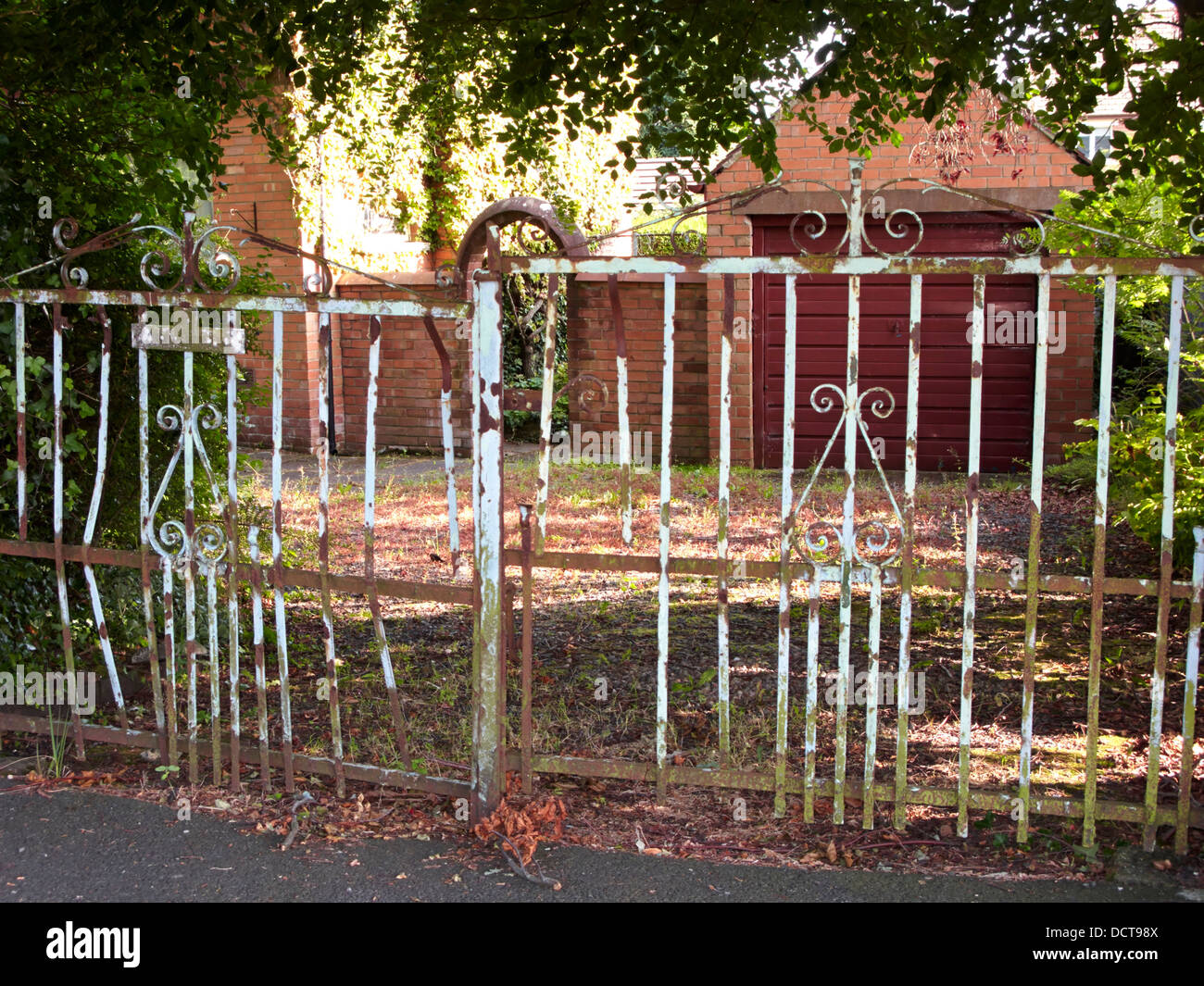 overgrown garden and rusty metal gate Stock Photo