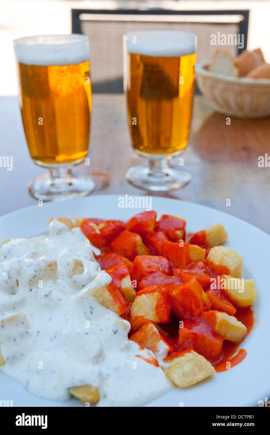 Spanish appetizer: Alioli and Bravas potatoes with two glasses of lager in a summer terrace. Madrid, Spain. Stock Photo