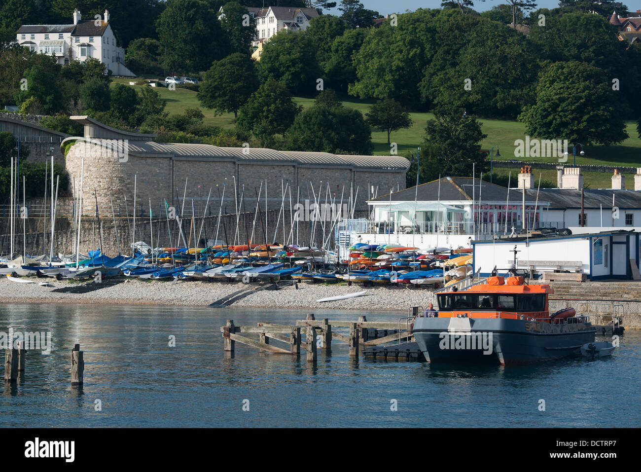 A view of the Swanage yacht club as seen from the pier. An orange and grey dive boat can be seen moored in the foreground near t Stock Photo