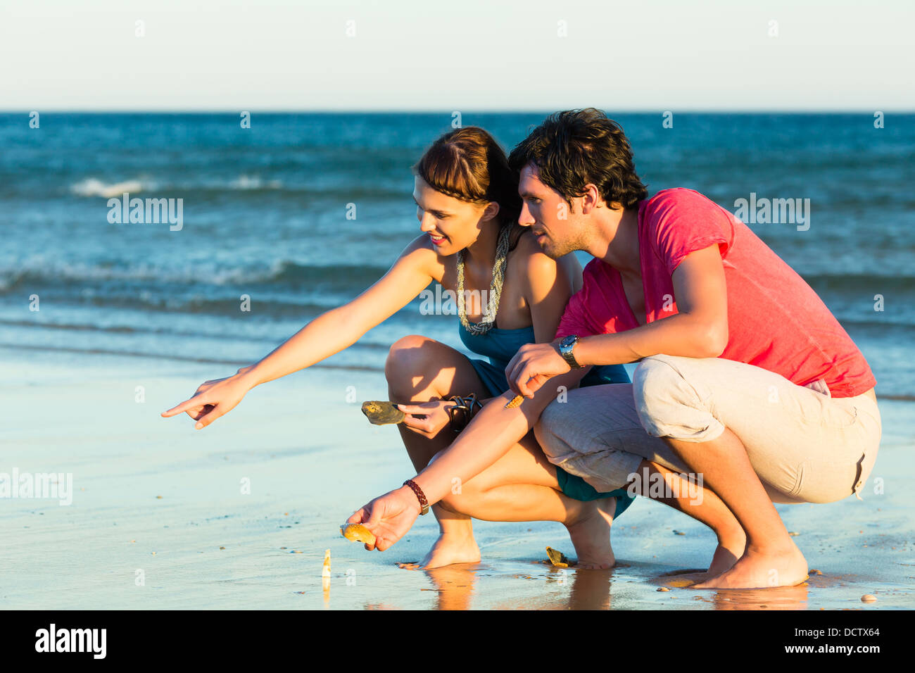 Man and woman, couple, enjoying the romantic sunset on a beach by the ...