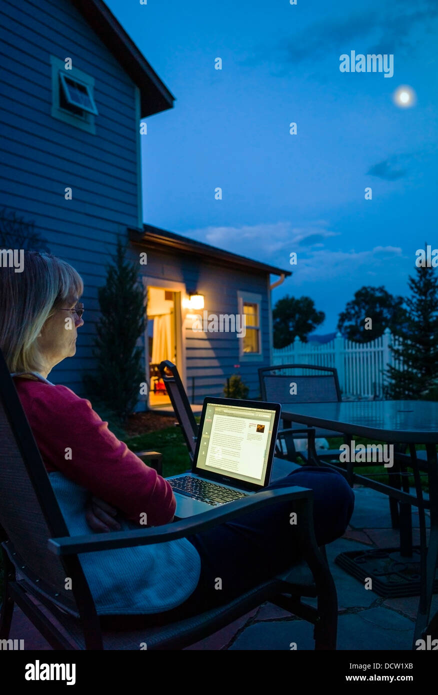 Woman working at home on laptop computer at dusk Stock Photo