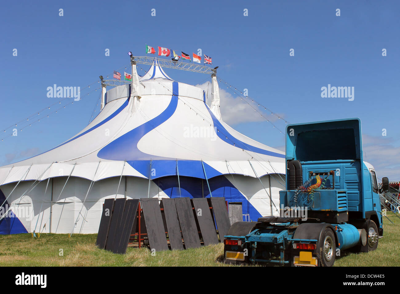 Blue and white circus tent with articulated lorry in foreground. Stock Photo