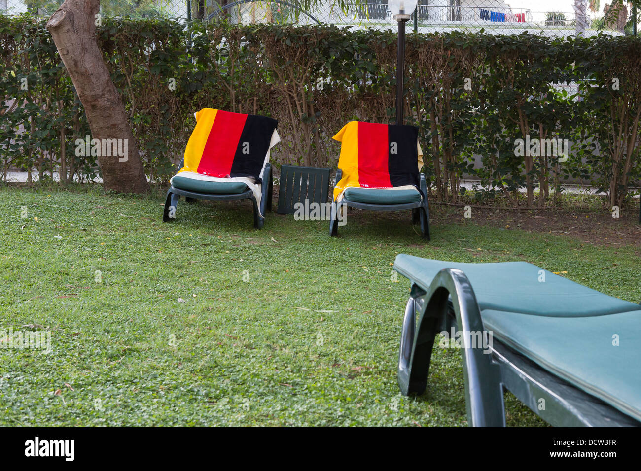 Towels in the colours of the German flag are used to reserve sun loungers at a hotel Stock Photo