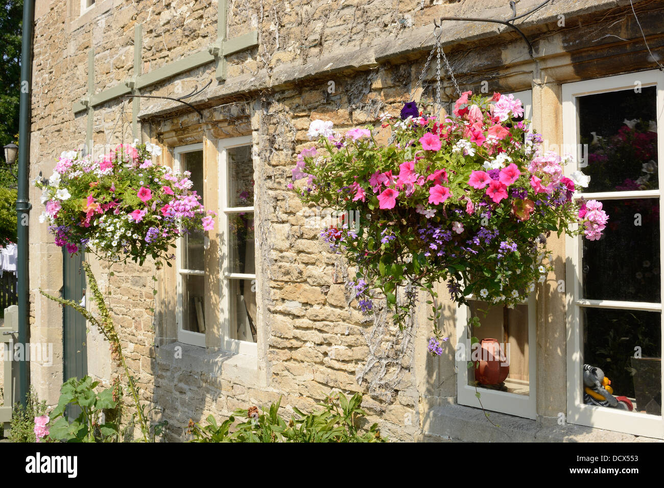 Stone cottage with hanging flower baskets in front of windows ...