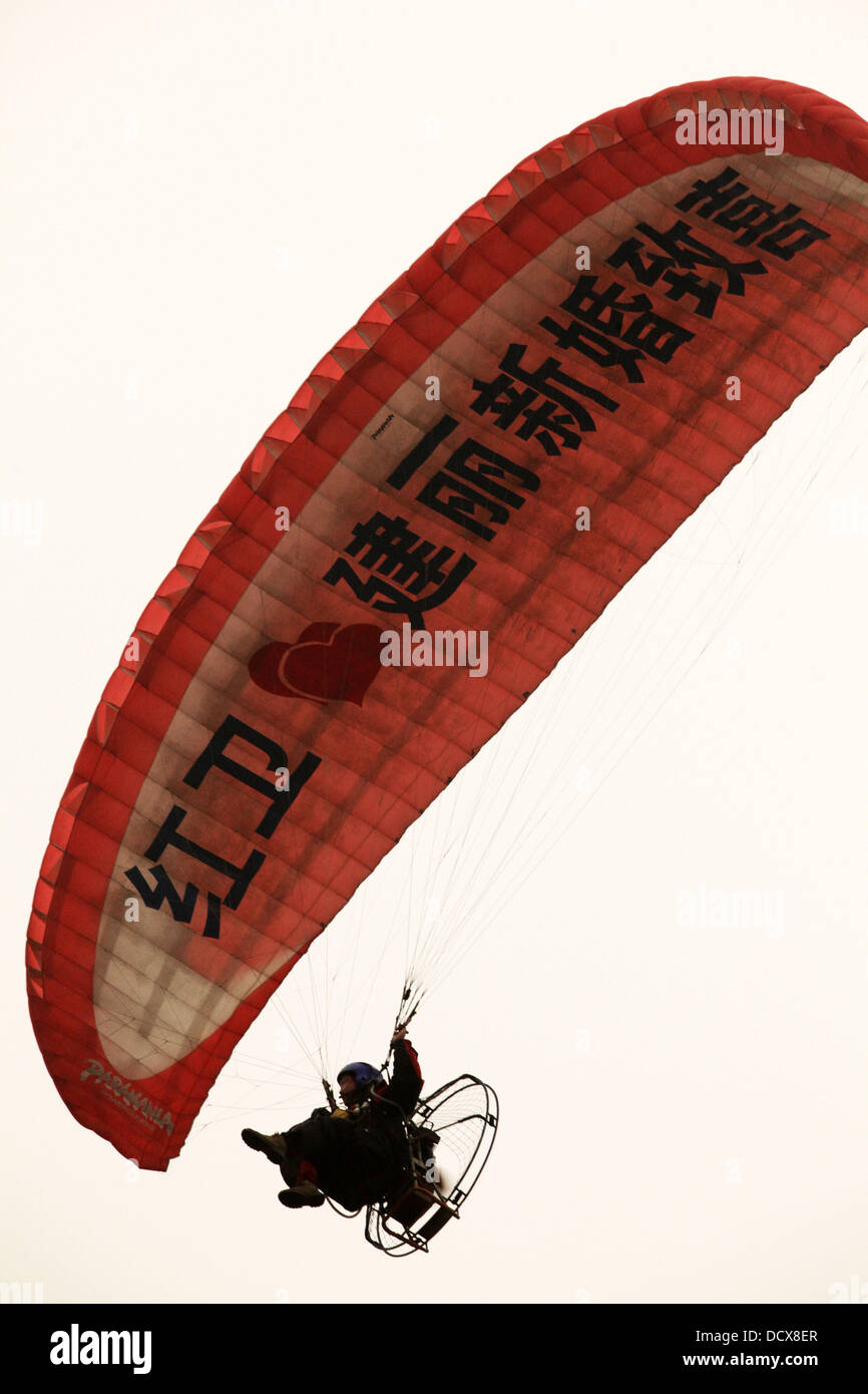 Love is in the air!  Bridegroom Zhao Weihong shows his love by flying a motorized paraglider in the sky for his bride Cao Xinli on there wedding day. The bride had a big surpise after seeing her future husband flying in the air above their wedding car   C Stock Photo