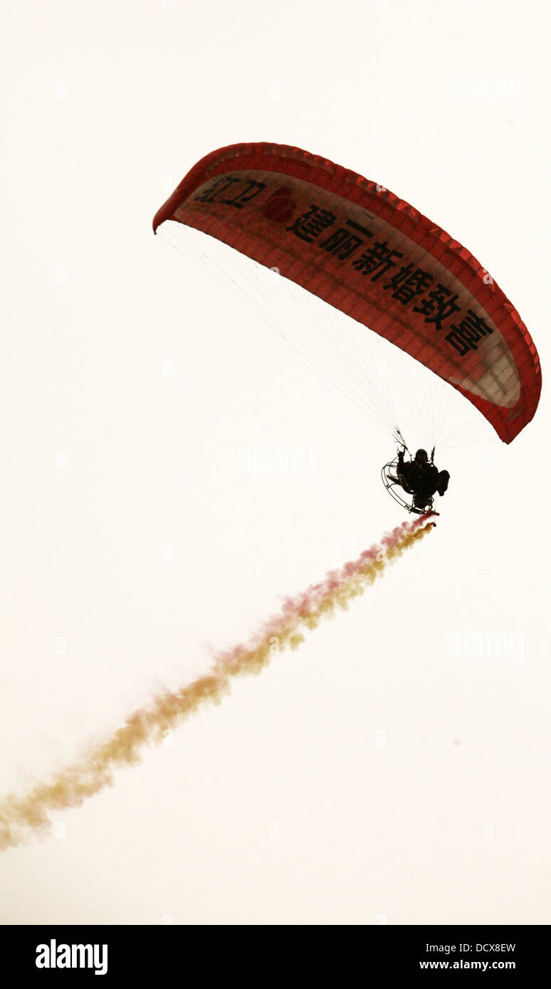 Love is in the air!  Bridegroom Zhao Weihong shows his love by flying a motorized paraglider in the sky for his bride Cao Xinli on there wedding day. The bride had a big surpise after seeing her future husband flying in the air above their wedding car   C Stock Photo