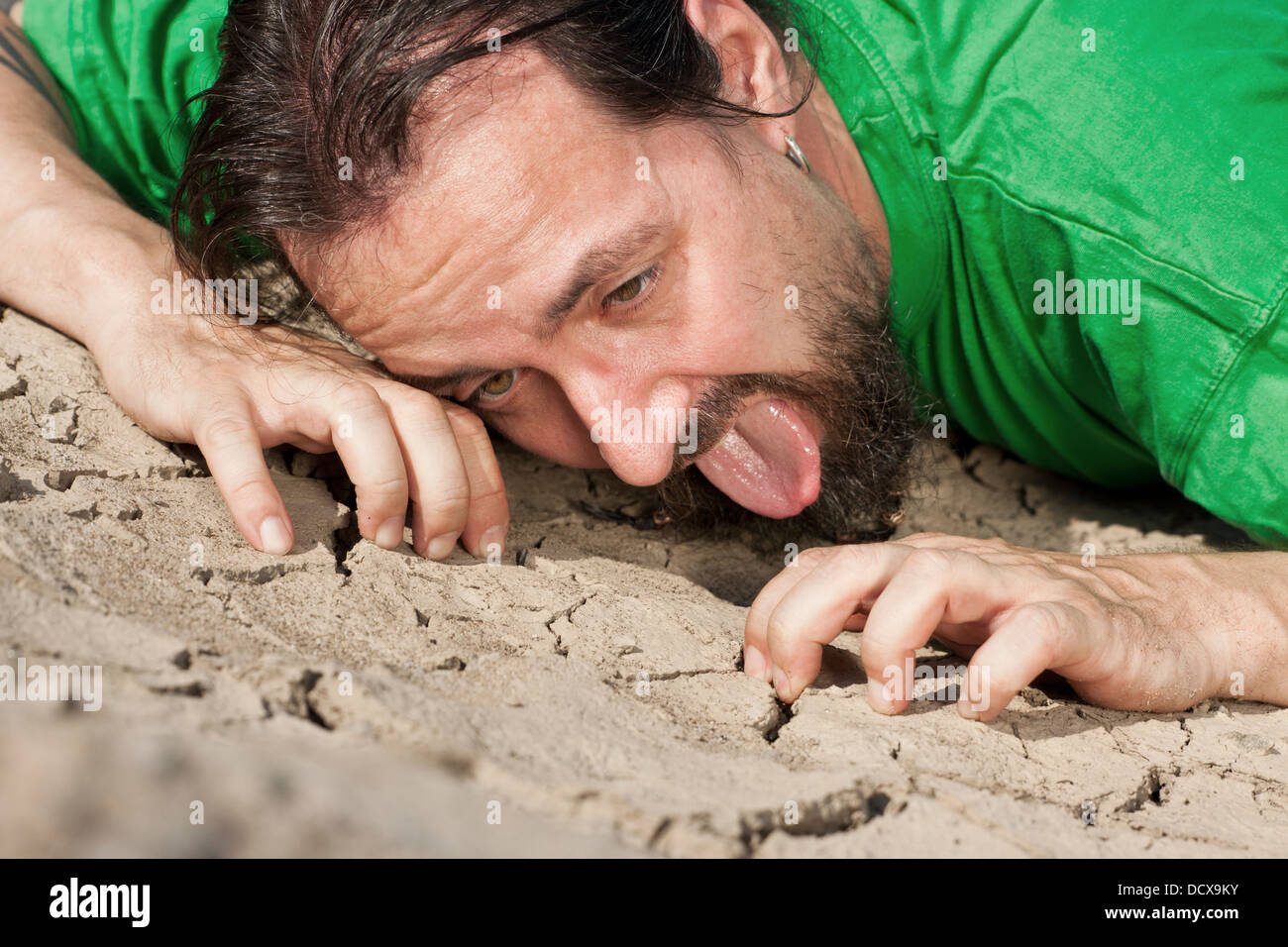 Thirsty long haired man on parched soil Stock Photo